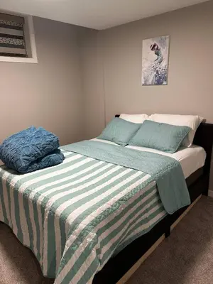 a bedroom with a bed with a striped blanket at Newly Built 2-Bedroom, 2 full bath Basement Suite in Calgary