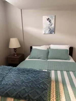 a bedroom with a bed and a lamp and a picture at Newly Built 2-Bedroom, 2 full bath Basement Suite in Calgary