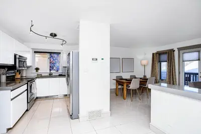 a kitchen with white appliances and a dining room at Chic Central 4BDRM Home-King Bed-AirHockey-Mins DT in Edmonton