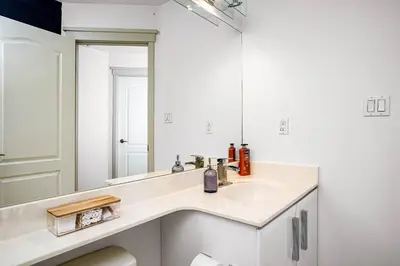 a white bathroom with a sink and a mirror at Chic Central 4BDRM Home-King Bed-AirHockey-Mins DT in Edmonton