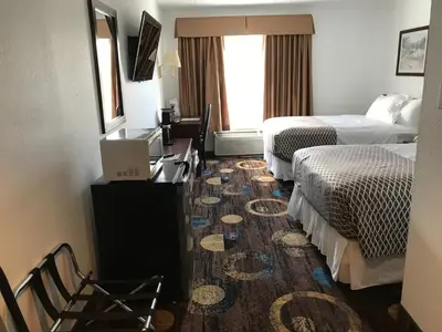 a hotel room with two beds and a desk at Stonebridge Hotel in Fort McMurray