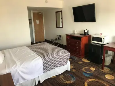 a hotel room with a bed and a dresser and a television at Stonebridge Hotel in Fort McMurray