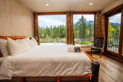a bedroom with a large bed and a large window at River Safari Bear Den in Blue River