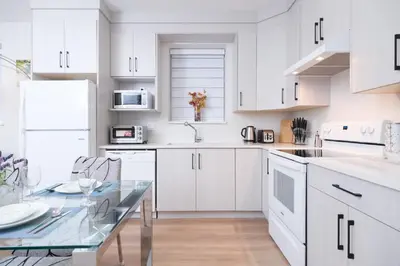 a white kitchen with white cabinets and a glass table at Newly Built Cozy 2BR Suite Langley Event Center in Langley