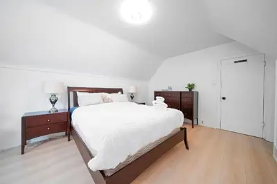 a white bedroom with a large bed and two night stands at Cozy three bedroom House in Vancouver West in Vancouver