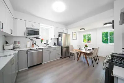 a kitchen with white cabinets and a table with chairs at Cozy three bedroom House in Vancouver West in Vancouver