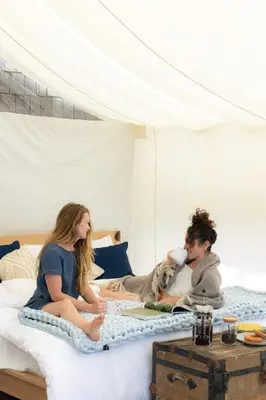 two women sitting on a bed with a dog at Lux Remote Glamping Hideaway in Ucluelet