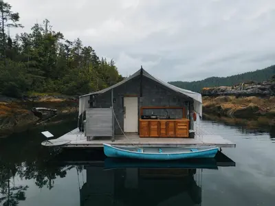 a small house on a dock with a boat on the water at Lux Remote Glamping Hideaway in Ucluelet