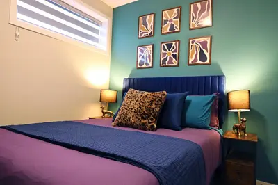 a bedroom with a purple bed with paintings on the wall at Edgemont Escape Large Groups, River Cree, WEM, Disney in Edmonton