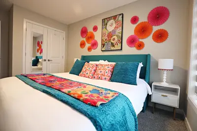 a bedroom with a bed with a colorful blanket on it at Edgemont Escape Large Groups, River Cree, WEM, Disney in Edmonton