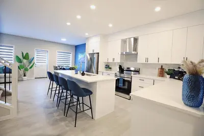 a kitchen with white cabinets and a island with bar stools at Edgemont Escape Large Groups, River Cree, WEM, Disney in Edmonton