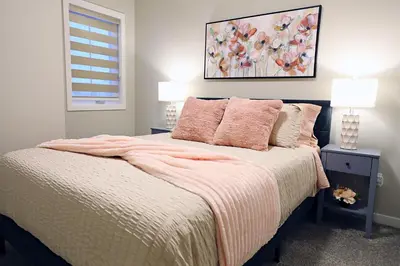 a bedroom with a bed with pink pillows and a painting at Edgemont Retreat, Groups, River Cree, WEM, Disney in Edmonton