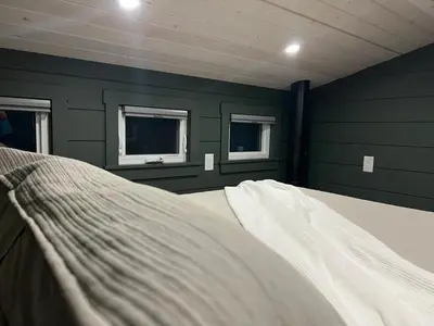a bed in a room with green walls and windows at Sagebrush Caboose in Okanagan Falls
