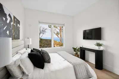 a white bedroom with a large bed and a window at Mountain Suite - Ocean View Fire Pit - Fully Equipped Kitchen - WD in Nanaimo
