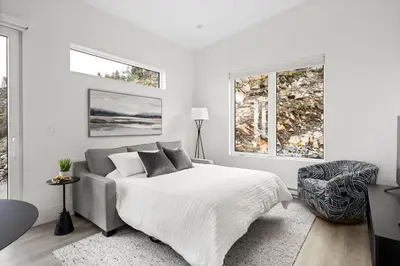a white bedroom with a bed and a window at Mountain Suite - Ocean View Fire Pit - Fully Equipped Kitchen - WD in Nanaimo