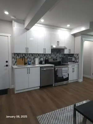 a kitchen with white cabinets and stainless steel appliances at Lovely home in Northwest Calgary in Calgary