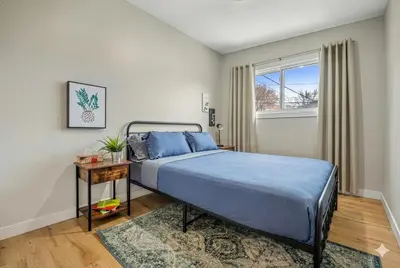 a bedroom with a bed with blue sheets and a window at Comfy, Cozy, Central Calgary, 2BR and 1BTH in Calgary