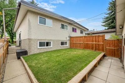 a backyard with a wooden fence and a lawn at Cozy and Welcoming 2BR Basement Suite In The Heart of Calgary in Calgary