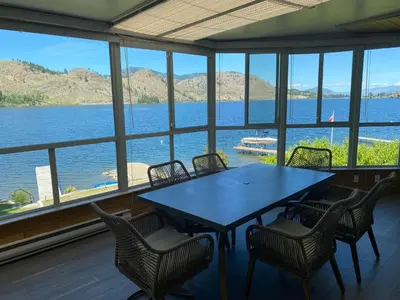 a table and chairs in a room with a view of the water at Skaha Lakefront Inn in Okanagan Falls