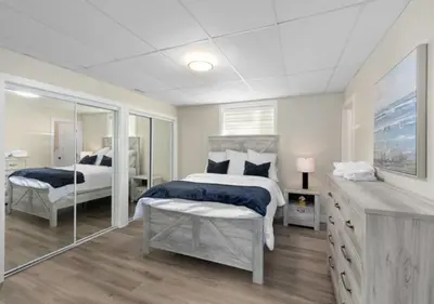 a white bedroom with two beds and a mirror at Skaha Lakefront Inn in Okanagan Falls