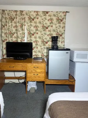 a room with a desk with a television and a microwave at Sunrise Motel in Consort