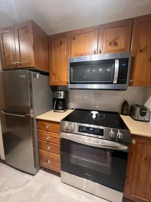 a kitchen with a stove and a microwave at Main Village, Ski-in Ski-out, Hot Tub, Condo in Sun Peaks