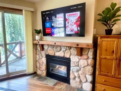 a fireplace in a living room with a tv above it at Main Village, Ski-in Ski-out, Hot Tub, Condo in Sun Peaks