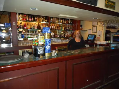 a woman standing behind a bar in a pub at Super 8 by Wyndham Fox Creek in Fox Creek