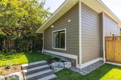 a home with a yard with stairs next to a house at Cozy Saanich Cottage ideal location to UVIC and Downtown in Victoria