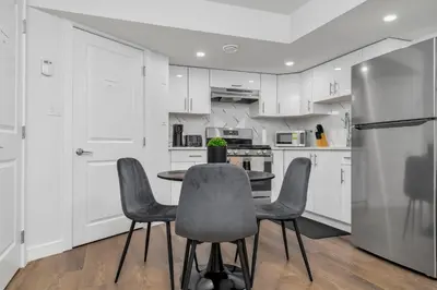 a kitchen with white cabinets and a table and chairs at Private Chic Orchard Getaway in Edmonton