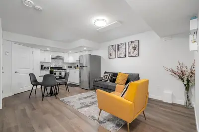 a living room with a yellow couch and a kitchen at Private Chic Orchard Getaway in Edmonton