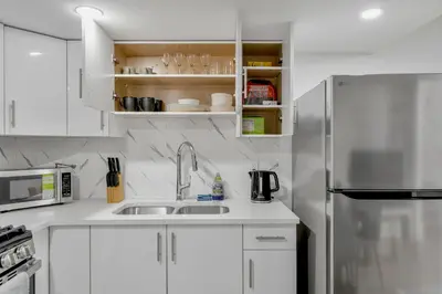 a kitchen with white cabinets and a stainless steel refrigerator at Private Chic Orchard Getaway in Edmonton