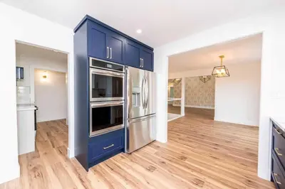 a kitchen with blue cabinets and a wooden floor at Walkout Bungalow with Pond Views in Balzac