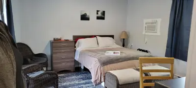 a bedroom with a bed with a dresser and a chair at Riverside Court RV and Cabins in Grand Forks