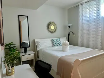 a white bedroom with a bed and a mirror at Global Family Canada in Calgary