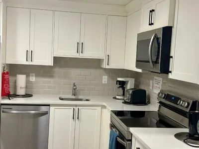 a kitchen with white cabinets and stainless steel appliances at Global Family Canada in Calgary