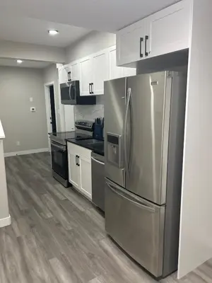 a kitchen with a stainless steel refrigerator and white cabinets at Entire 2 Ensuite Bedrooms in a Basement in Edmonton