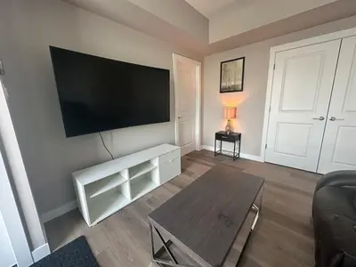 a living room with a flat screen tv on a wall at Cozzy & Brand New Apartment, Near Banff Hwy in Calgary