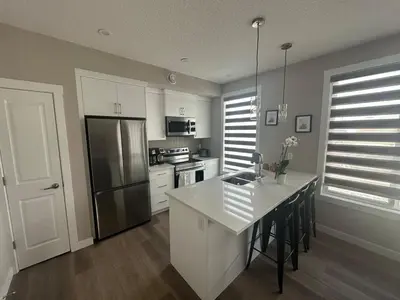 a kitchen with white cabinets and a stainless steel refrigerator at Cozzy & Brand New Apartment, Near Banff Hwy in Calgary