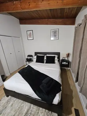 a bedroom with a bed with white sheets and black pillows at P&N Suites - Queen Room- DUBAI in Edmonton