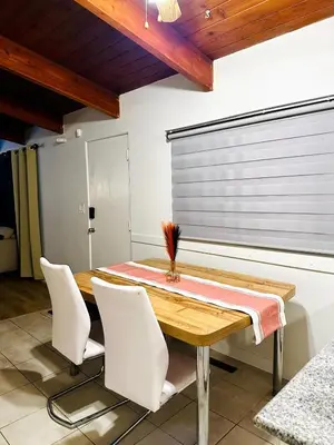 a dining room with a wooden table and white chairs at P&N Suites - Queen Room- DUBAI in Edmonton