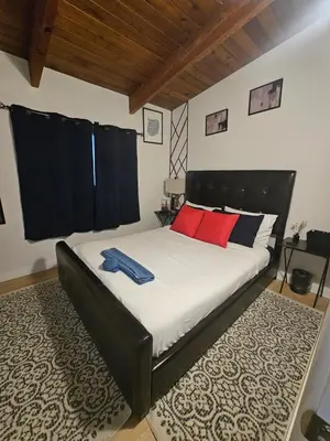 a bedroom with a bed with red and blue pillows at P&N Suites - DELUXE QUEEN ROOM- LONDON in Edmonton