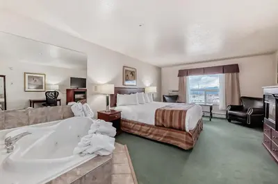 a hotel room with a bed and a bath tub at Grande Cache Inn & Suites in Grande Cache
