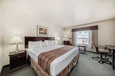 a hotel room with a large bed and a desk at Grande Cache Inn & Suites in Grande Cache