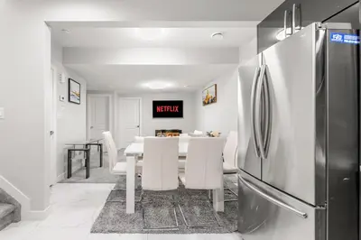 a kitchen and dining room with a table and a refrigerator at Entire 1 bed and Den Near YEG International Airport in Nisku