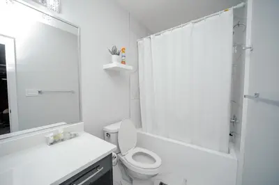 a white bathroom with a toilet and a shower at Entire 1 bed and Den Near YEG International Airport in Nisku