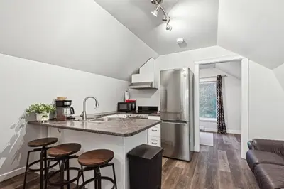 a kitchen with a stainless steel refrigerator and stools at Quiet and rural apartment in the country in Cobble Hill