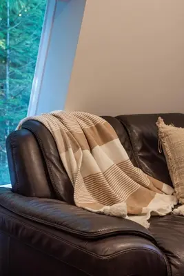 a blanket sitting on top of a leather couch at Quiet and rural apartment in the country in Cobble Hill