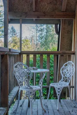 two chairs and a table on the porch of a cabin at Quiet and rural apartment in the country in Cobble Hill