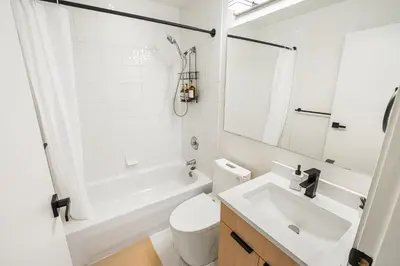 a white bathroom with a tub and a toilet and a sink at Modern & Cozy Home in the Heart of Downtown Vancouver in Vancouver